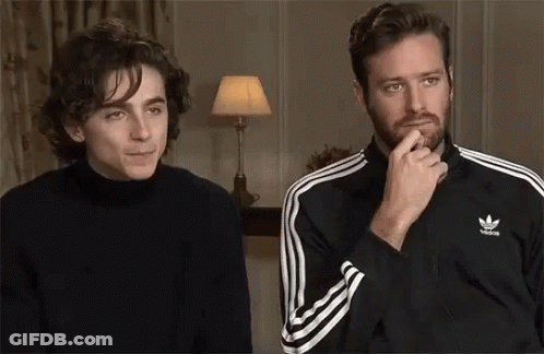 Two Men Are Sitting Next To Each Other In A Room . One Of The Men Is Wearing A Black Adidas Jacket . GIF