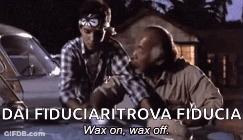 Two Men Are Sitting Next To Each Other In Front Of A Car And Talking . GIF