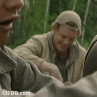 Two Men Are Sitting Next To Each Other In The Woods . GIF