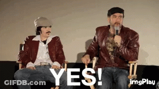 Two Men Are Sitting Next To Each Other On A Couch And One Is Holding A Microphone And The Other Is Saying Yes . GIF