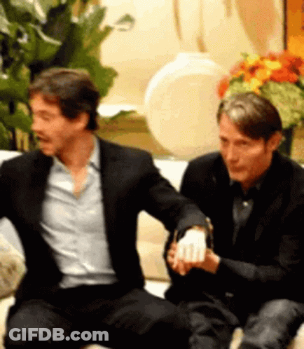 Two Men Are Sitting Next To Each Other On A Couch Holding Hands . GIF