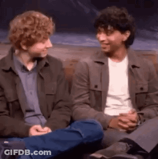 Two Men Are Sitting Next To Each Other On A Couch Talking To Each Other . GIF