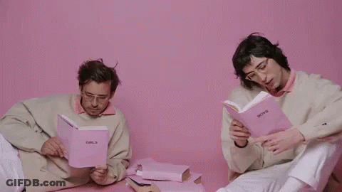 Two Men Are Sitting Next To Each Other Reading Books . GIF