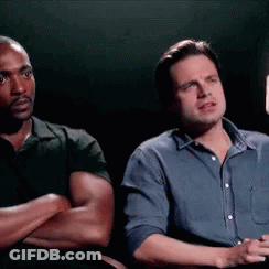Two Men Are Sitting Next To Each Other With Their Arms Crossed And Looking At Something . GIF