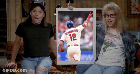 Two Men Are Sitting On A Couch And One Is Holding A Framed Picture Of Schwarber 12 GIF