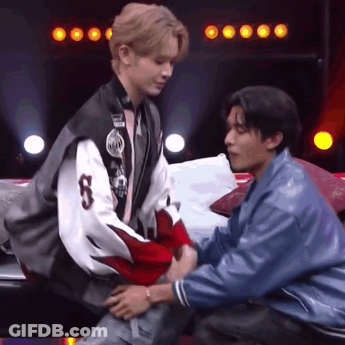 Two Men Are Sitting On A Couch And One Of Them Is Holding The Other 'S Arm . GIF