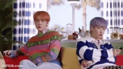 Two Men Are Sitting On A Couch In A Living Room . GIF