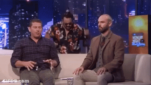 Two Men Are Sitting On A Couch In Front Of A Sign That Says Monday Night GIF