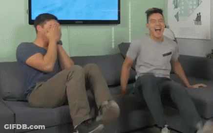 Two Men Are Sitting On A Couch Laughing And Covering Their Eyes GIF