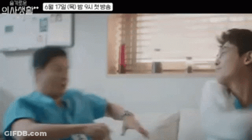 Two Men Are Sitting On A Couch Talking To Each Other In A Living Room . GIF