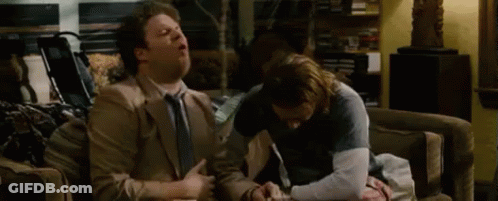 Two Men Are Sitting On A Couch Talking To Each Other . GIF