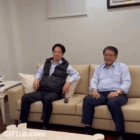 Two Men Are Sitting On A Couch With A Remote Control . GIF
