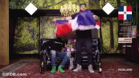 Two Men Are Sitting On A Couch With A Sign That Says Viceland On It GIF