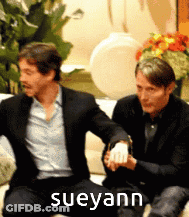 Two Men Are Sitting On A Couch With The Name Sueyann On The Bottom Right GIF