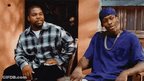 Two Men Are Sitting On A Porch Talking To Each Other . One Of The Men Is Wearing A Blue Hat . GIF