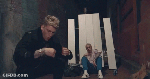Two Men Are Sitting On The Ground And One Is Smoking A Cigarette . GIF