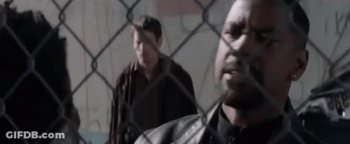 Two Men Are Standing Behind A Chain Link Fence . GIF