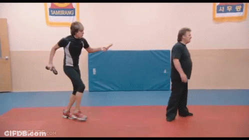 Two Men Are Standing In A Gym With A Sign That Says Samurang On It GIF