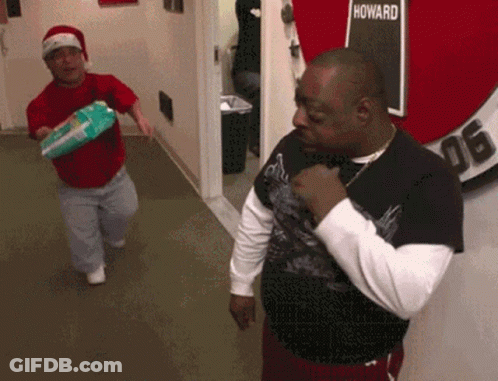 Two Men Are Standing In A Hallway With A Sign That Says Howard GIF