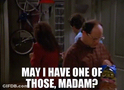 Two Men Are Standing In A Kitchen Talking To Each Other . One Of The Men Is Holding A Bag Of Chips . GIF
