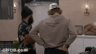 Two Men Are Standing In A Kitchen Talking To Each Other . GIF