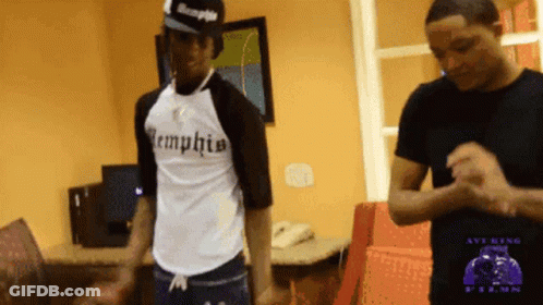 Two Men Are Standing In A Room And One Has A Shirt That Says Memphis On It GIF