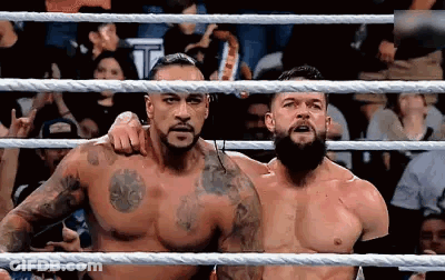 Two Men Are Standing In A Wrestling Ring . GIF