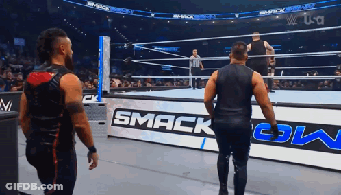Two Men Are Standing In A Wrestling Ring With A Sign That Says Smack Down GIF