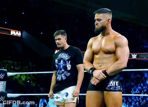 Two Men Are Standing In A Wrestling Ring With One Wearing A Shirt That Says " Storm Rider " On It GIF