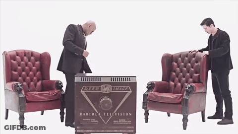 Two Men Are Standing In Front Of A Box That Says Radiola Television GIF