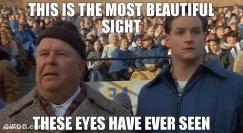 Two Men Are Standing In Front Of A Crowd Of People And Looking Up At The Sky . GIF