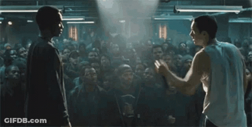 Two Men Are Standing In Front Of A Crowd Of People . GIF