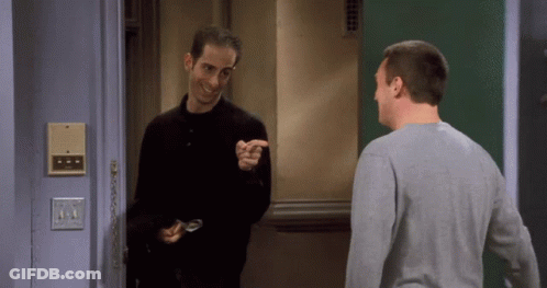 Two Men Are Standing In Front Of A Door And One Is Pointing GIF