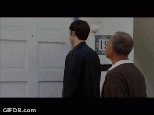 Two Men Are Standing In Front Of A Door With A Sign That Says 19 On It . GIF