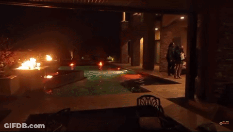 Two Men Are Standing In Front Of A Fire And One Of Them Is Wearing A Shirt That Says ' The Eagles ' On It GIF