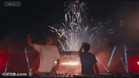 Two Men Are Standing In Front Of A Fireworks Display And The Words Coachella Are On The Bottom Left GIF