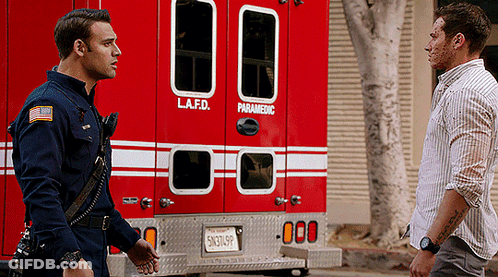 Two Men Are Standing In Front Of A Lafd Paramedic Vehicle GIF