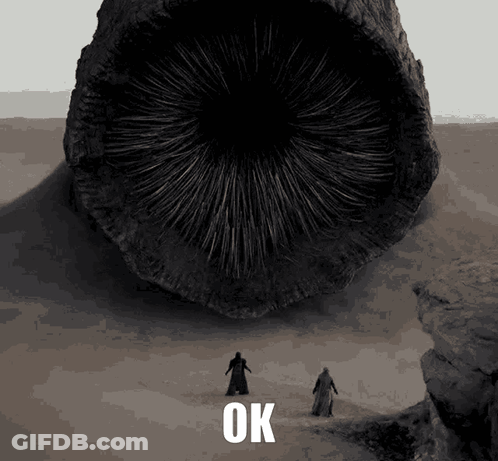 Two Men Are Standing In Front Of A Large Object That Says Ok On The Bottom GIF