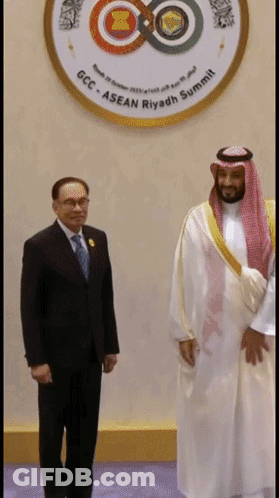 Two Men Are Standing In Front Of A Logo That Says Gcc Asean Riyadh Summit GIF