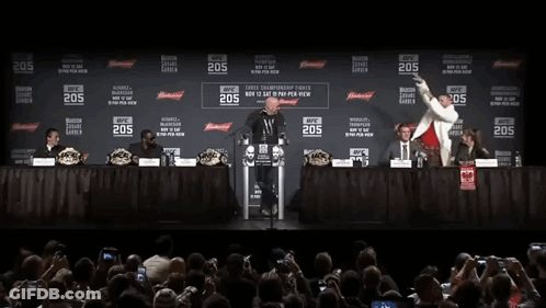 Two Men Are Standing In Front Of A Podium With The Number 205 On It . GIF
