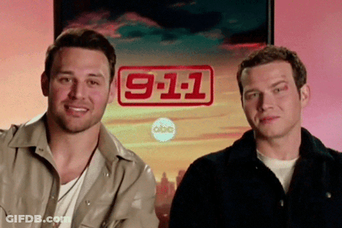 Two Men Are Standing In Front Of A Sign That Says 911 GIF