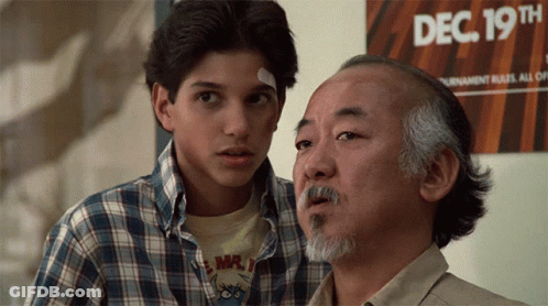 Two Men Are Standing In Front Of A Sign That Says Dec 19Th On It GIF