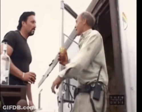 Two Men Are Standing In Front Of A Sign That Says ' Shield ' On It GIF
