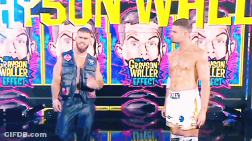 Two Men Are Standing In Front Of A Wall That Says Grayson Waller GIF