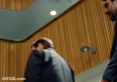 Two Men Standing In Front Of Wood Paneling GIF