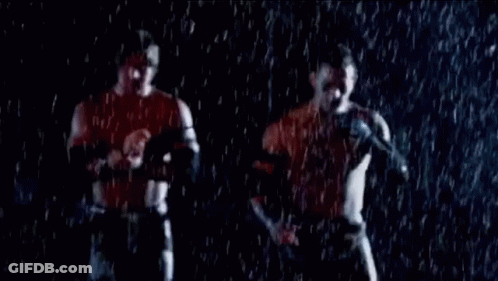 Two Men Are Standing In The Rain Holding Hands And Talking Into Microphones . GIF
