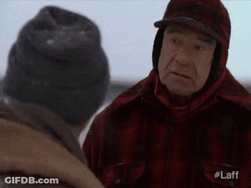Two Men Are Standing In The Snow Talking To Each Other . One Of The Men Is Wearing A Plaid Jacket And A Hat . GIF