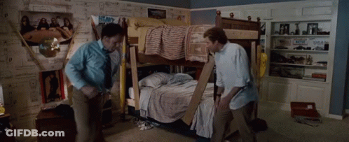 Two Men Are Standing Next To A Bunk Bed In A Room With Posters On The Wall GIF