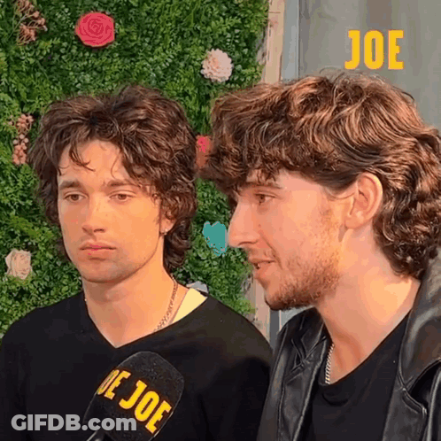 Two Men Are Standing Next To Each Other And One Has A Microphone With The Word Joe On It GIF