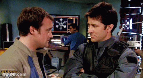 Two Men Standing One With Atlantis Patch GIF